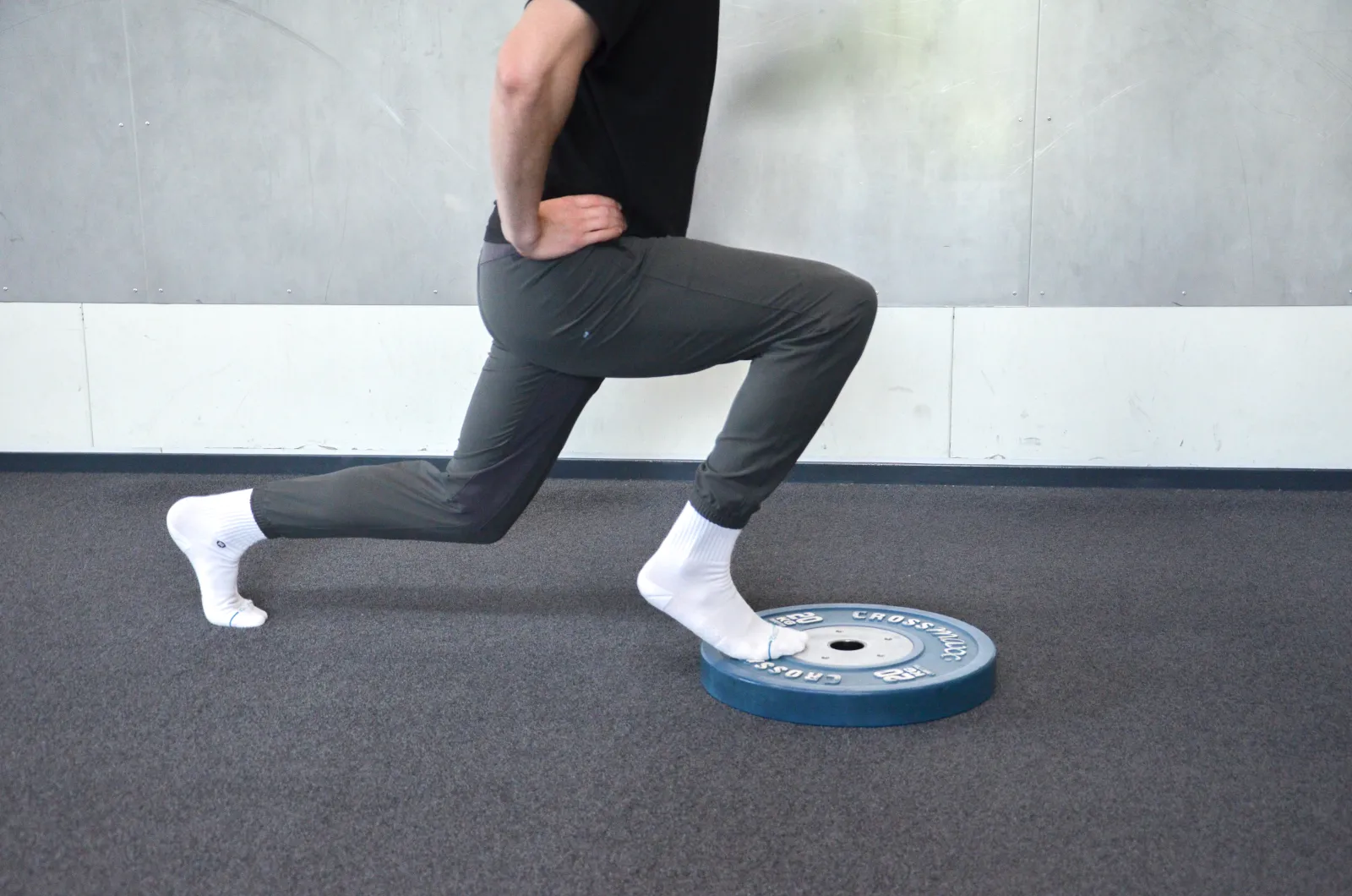 Jonge sporter doet een split squat als oefening bij knieklachten